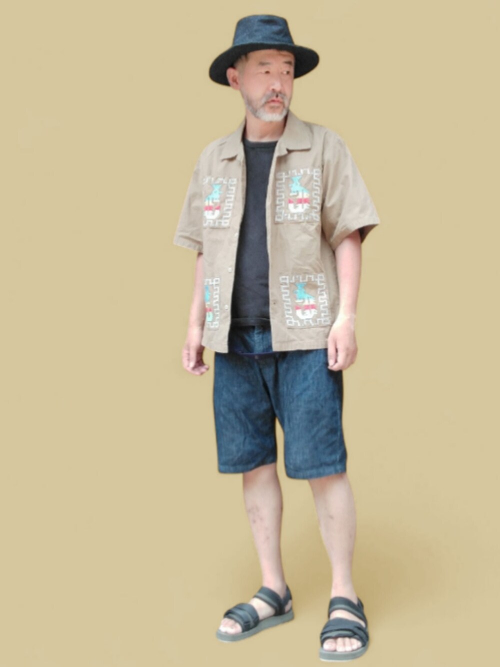 ブルー系のデニムパンツ、ブラック系のサンダル、ベージュ系のシャツ/ブラウスを着用したメンズの夏コーディネートの4枚目の写真