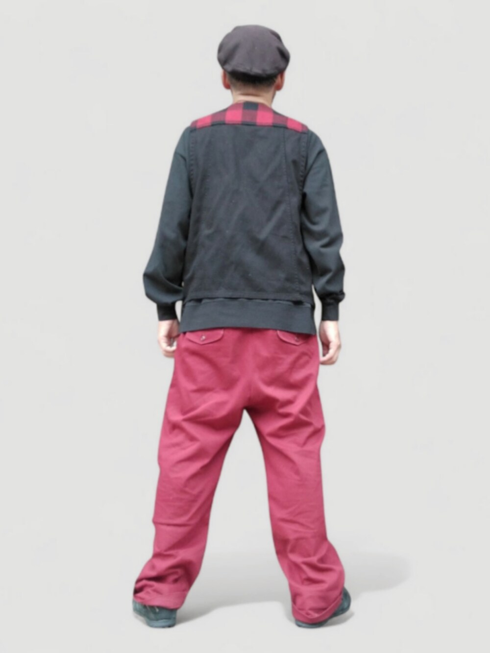 レッド系のチノパンツ、レッド系のベスト、ブラック系のスニーカーを着用したメンズの秋コーディネートの5枚目の写真