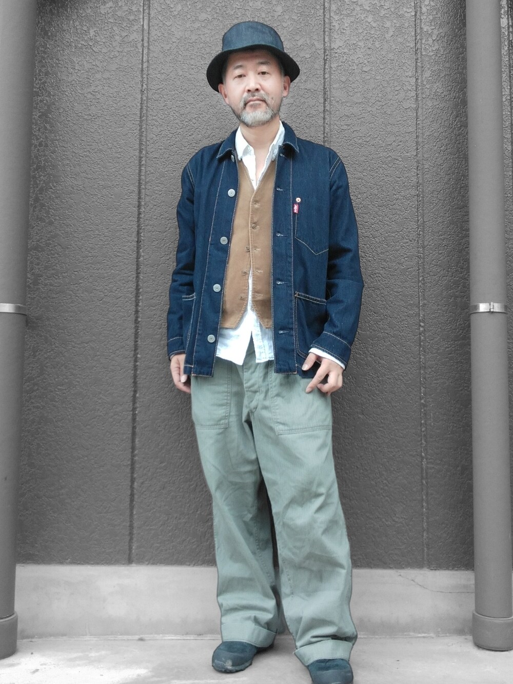 グリーン系のカーゴパンツ、ブルー系のデニムジャケット、ベージュ系のベストを着用したメンズの秋コーディネートの2枚目の写真