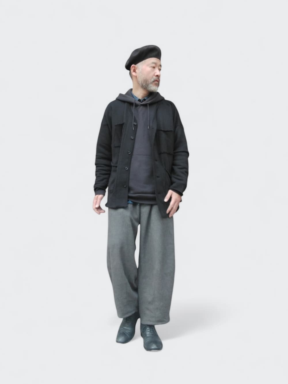 グレー系のパンツ、ブラック系のカーディガン/ボレロ、ブラック系のハンチング/ベレー帽を着用したメンズの春コーディネートの4枚目の写真