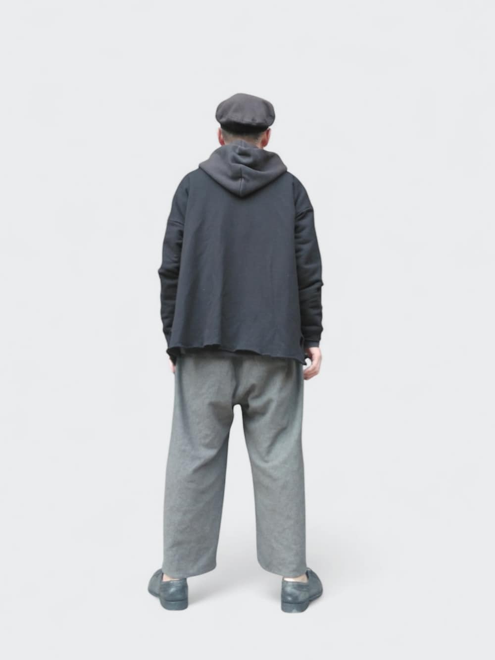 グレー系のパンツ、ブラック系のカーディガン/ボレロ、ブラック系のハンチング/ベレー帽を着用したメンズの春コーディネートの5枚目の写真