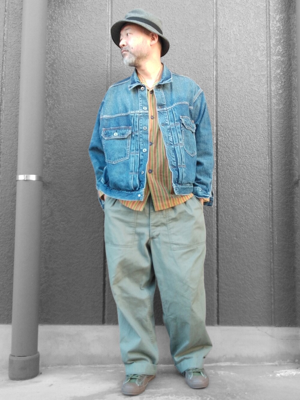 グリーン系のカーゴパンツ、ブラック系のスニーカー、ブルー系のデニムジャケットを着用したメンズの冬コーディネートの2枚目の写真