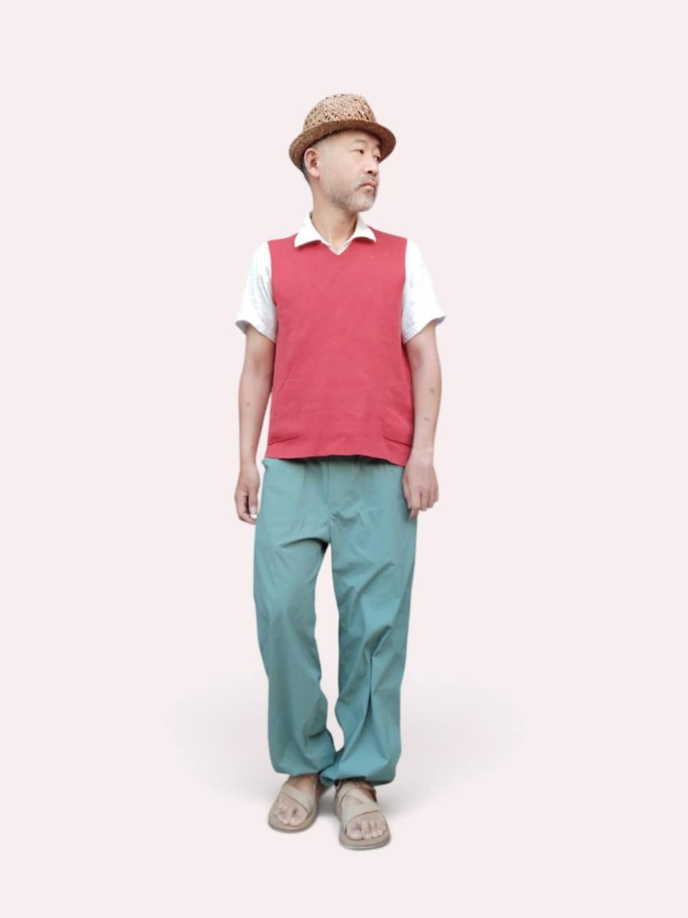 グリーン系のパンツ、ベージュ系のサンダル、レッド系のベストを着用したメンズの夏コーディネートの2枚目の写真