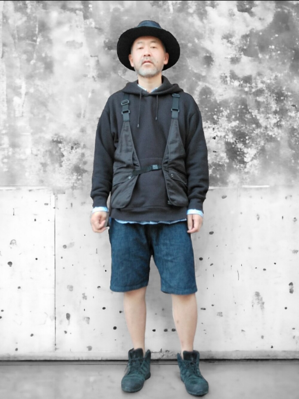 ブラック系のベスト、ブルー系のデニムパンツ、ブラック系のスニーカーを着用したメンズの春コーディネートの3枚目の写真