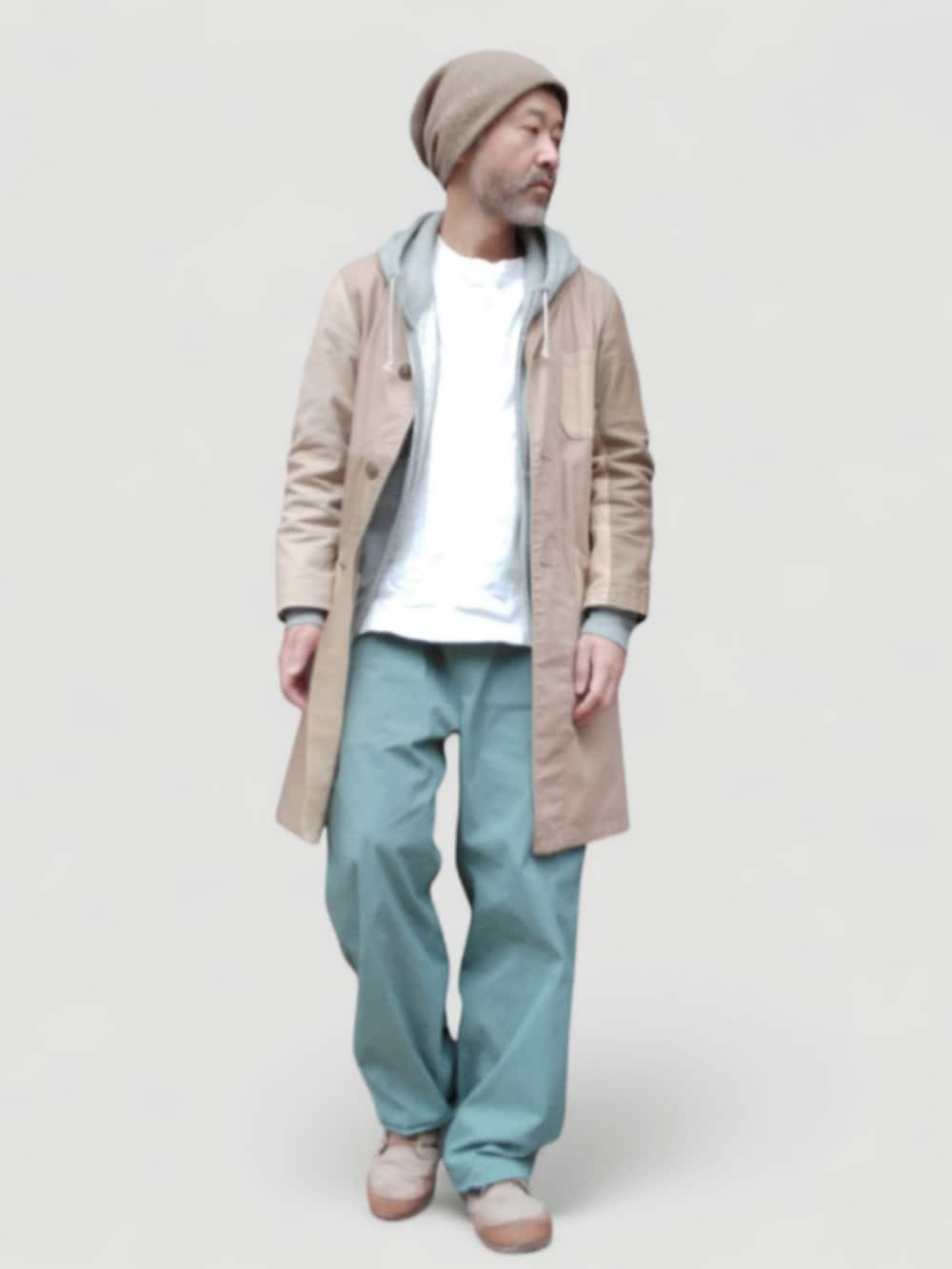 グリーン系のパンツ、ベージュ系のスニーカー、ベージュ系のステンカラーコートを着用したメンズの冬コーディネートの3枚目の写真