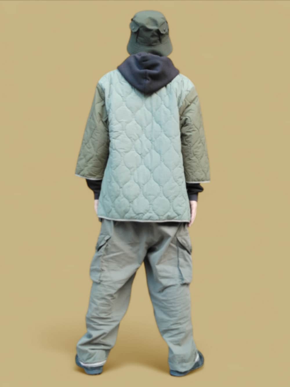 グリーン系のカーゴパンツ、ブラック系のパーカー、ブラック系のスニーカーを着用したメンズの秋コーディネートの5枚目の写真
