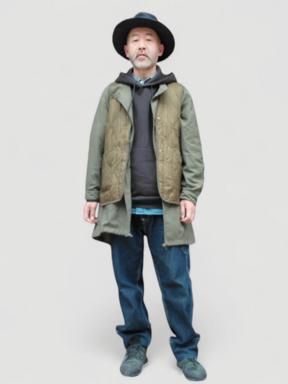 ブラック系のパーカー、グリーン系のベスト、ブルー系のデニムパンツを着用したメンズの秋コーディネートの4枚目の写真