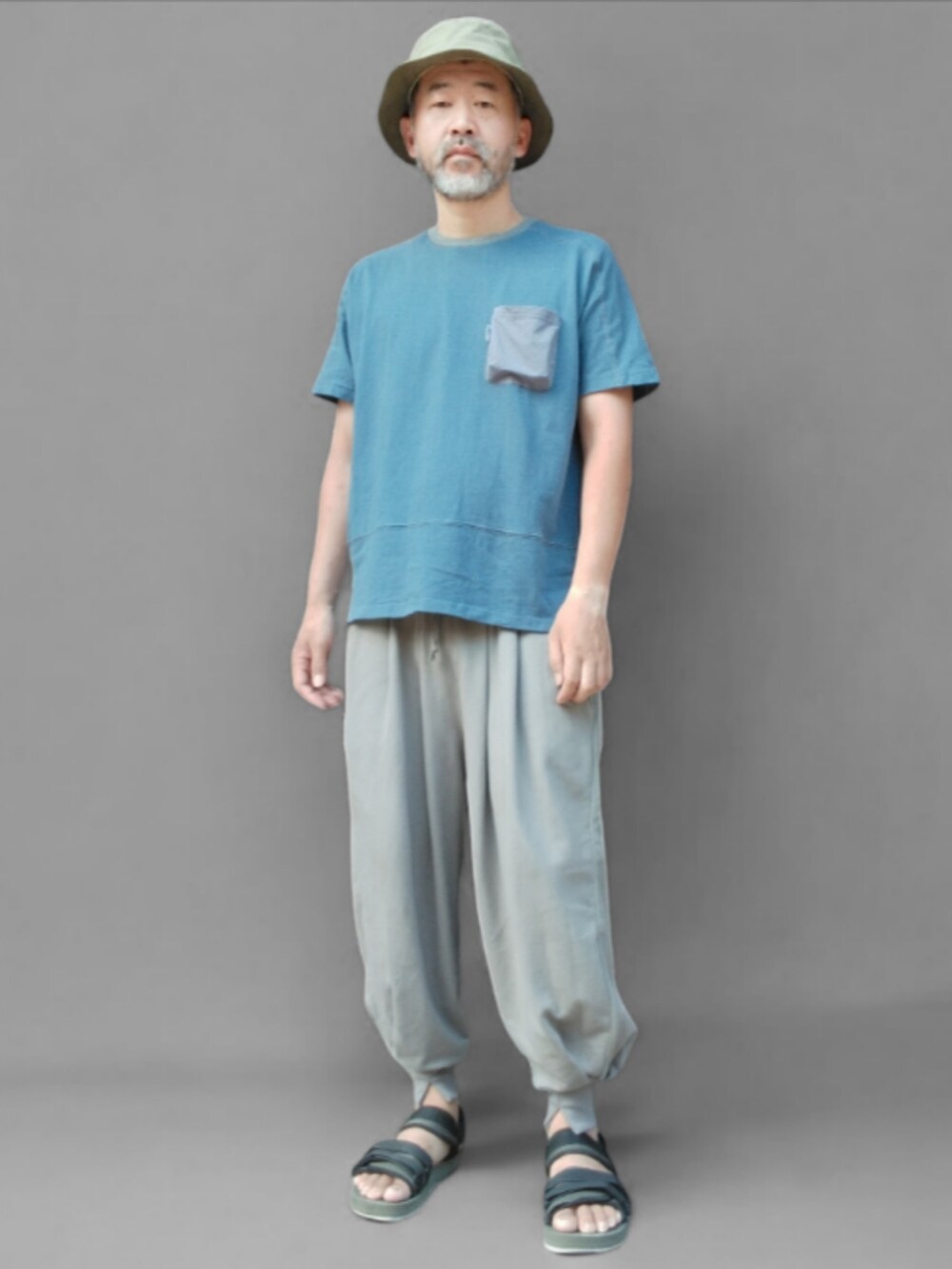 グレー系のスウェットパンツ、グリーン系のサンダル、ブルー系のTシャツ/カットソーを着用したメンズの夏コーディネートの3枚目の写真
