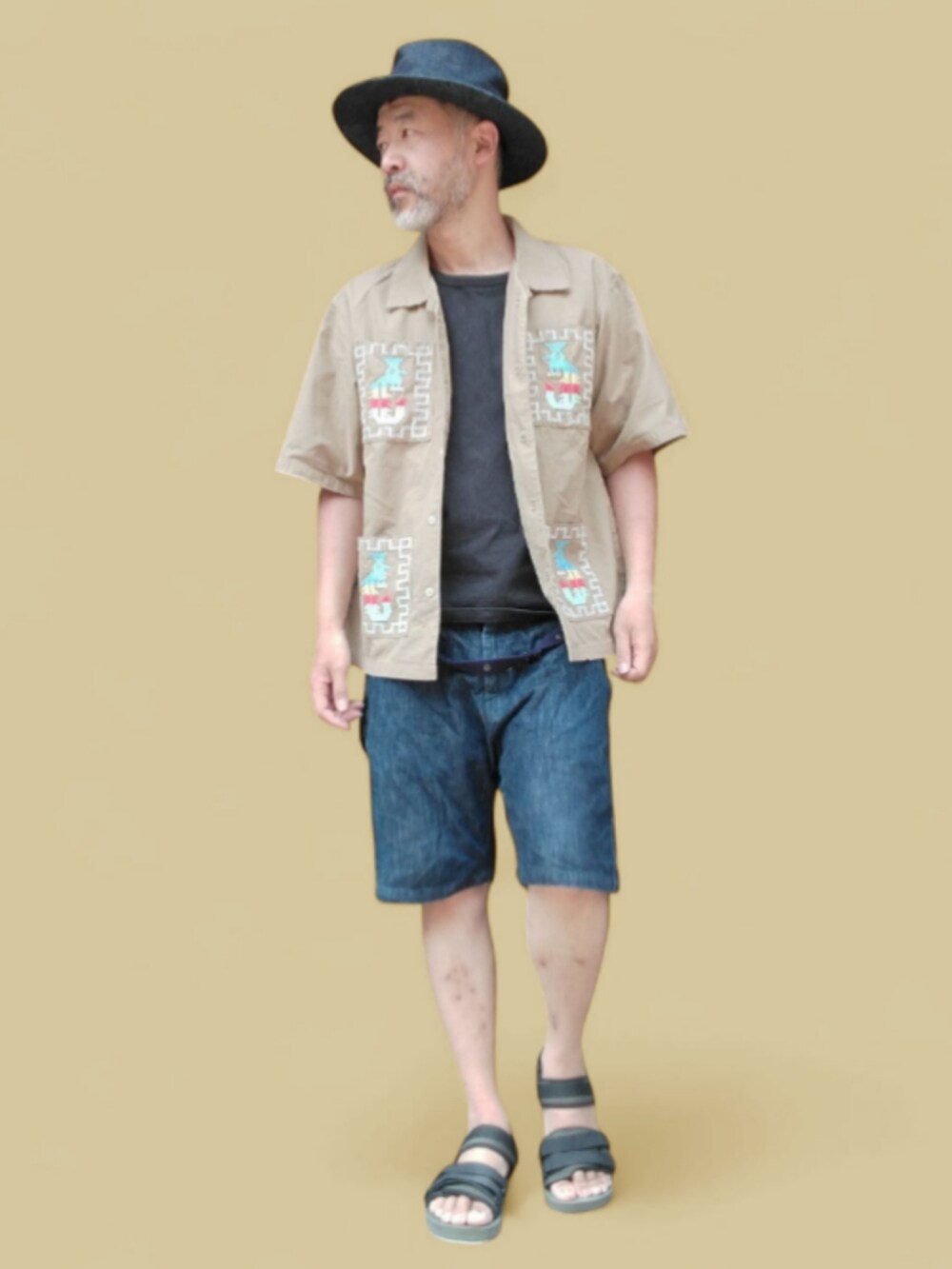 ブルー系のデニムパンツ、ブラック系のサンダル、ベージュ系のシャツ/ブラウスを着用したメンズの夏コーディネートの2枚目の写真