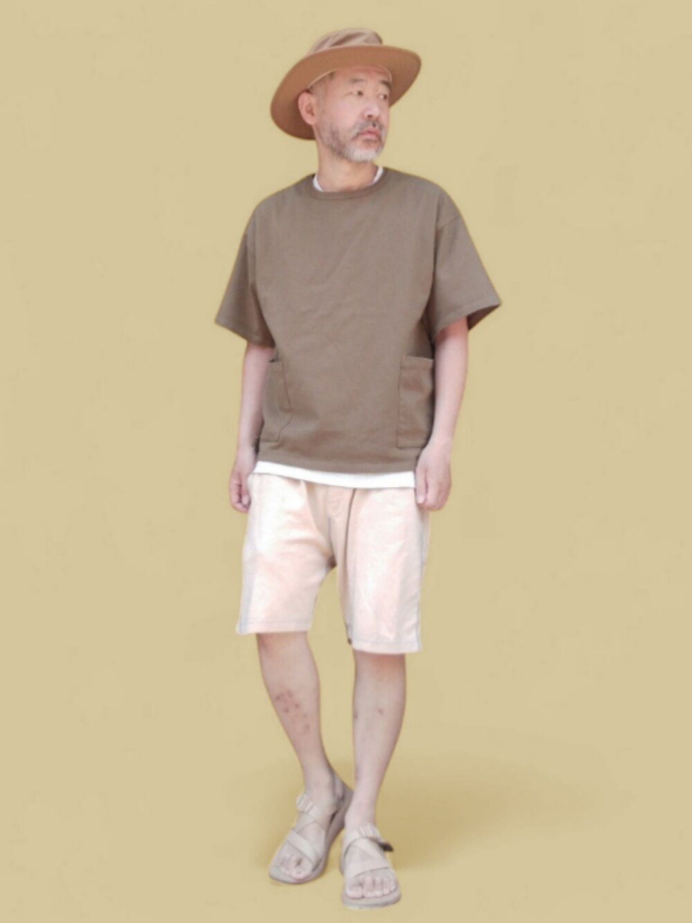 グリーン系のTシャツ/カットソー、イエロー系のパンツ、ベージュ系のサンダルを着用したメンズの夏コーディネートの3枚目の写真