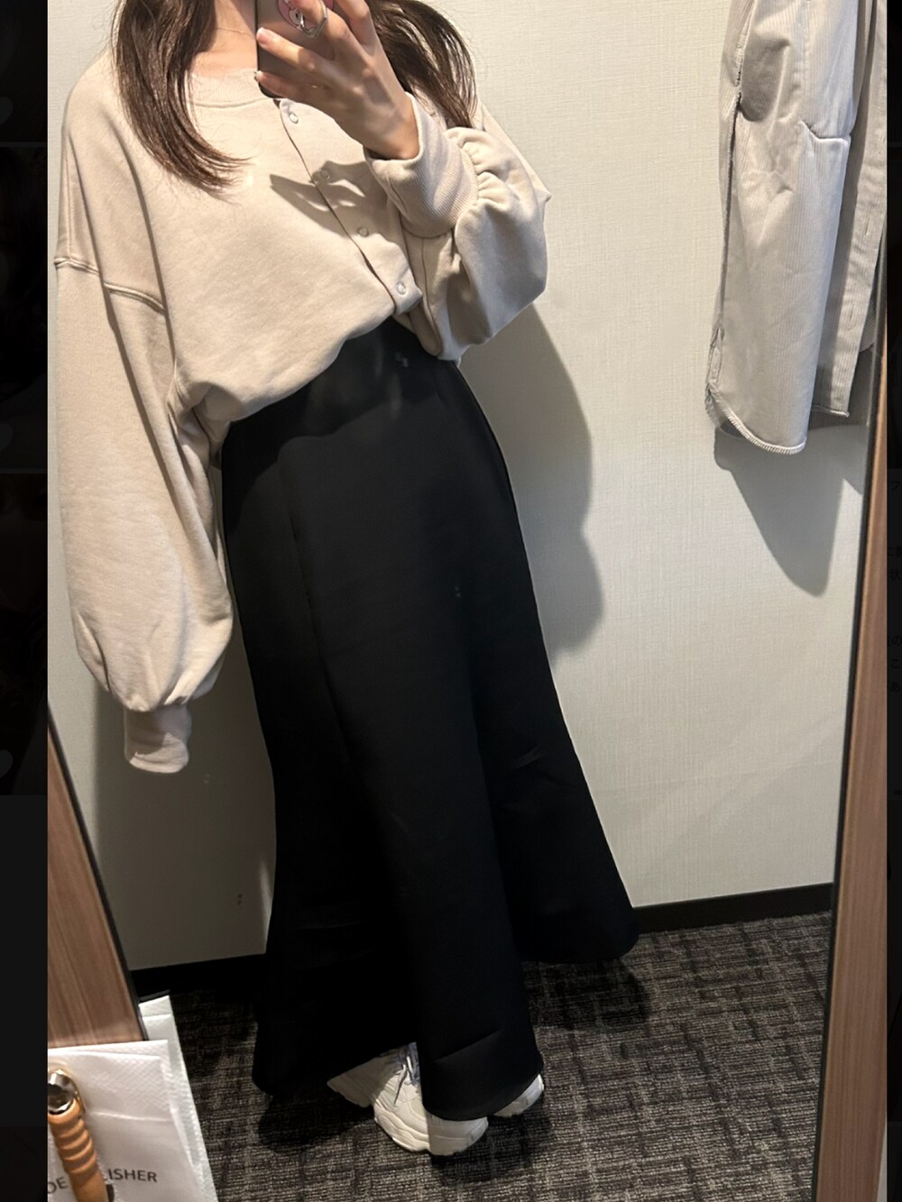 ブラック系のダウンジャケット/コート、ベージュ系のカーディガン/ボレロ、ブラック系のスカートを着用したレディースの秋コーディネートの2枚目の写真