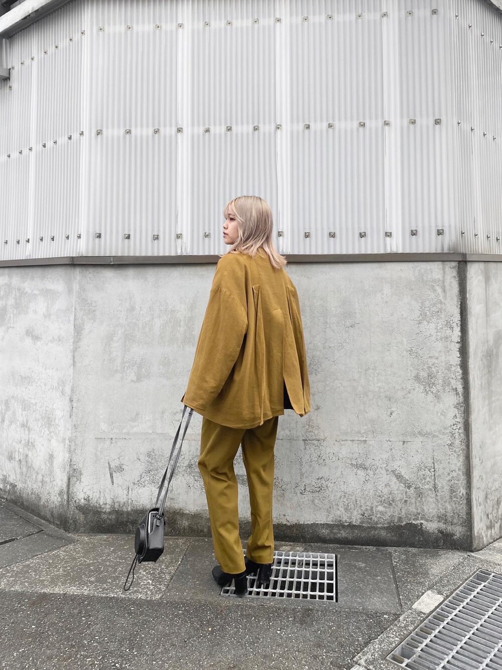 イエロー系のパンツ、イエロー系のジャケット/アウター、ブラック系のブーツを着用したレディースの冬コーディネートの2枚目の写真