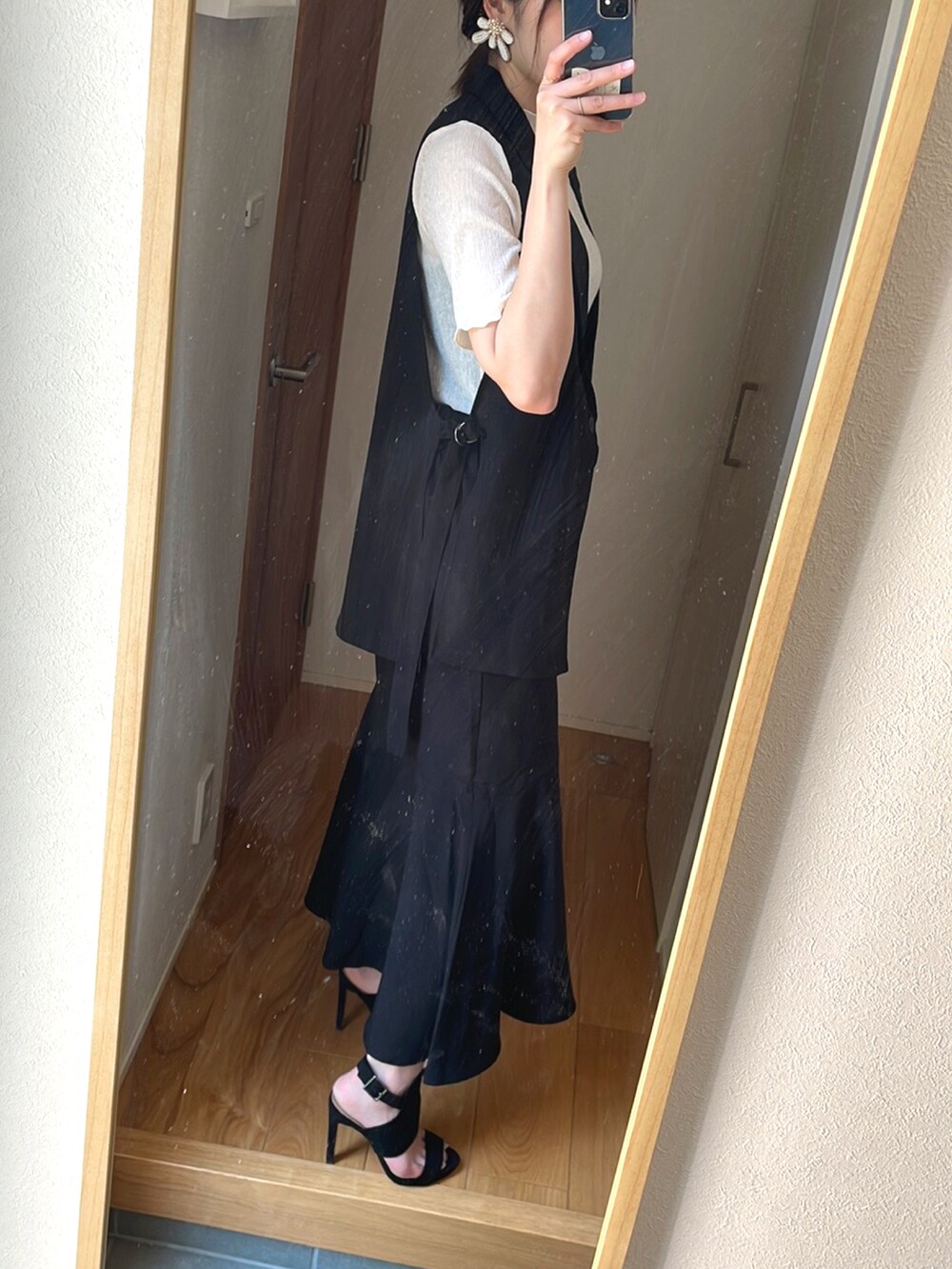 グレー系のバッグ、ブラック系のサンダル、ホワイト系のトップスを着用したレディースの春コーディネートの2枚目の写真