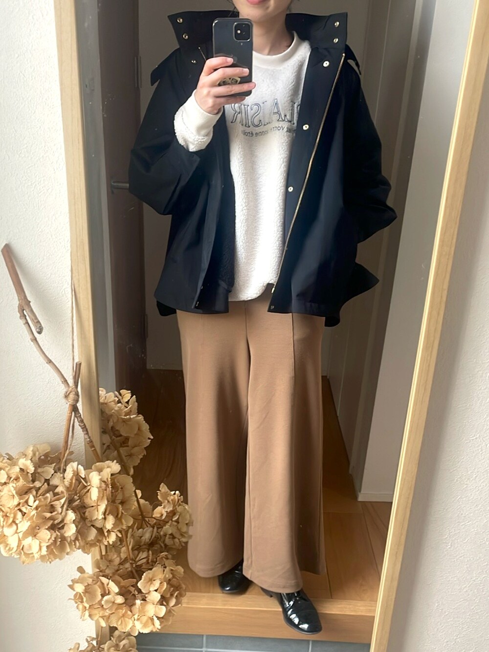 ブラック系のマウンテンパーカー、ブラック系のローファー、ホワイト系のスウェットを着用したレディースの春コーディネートの2枚目の写真