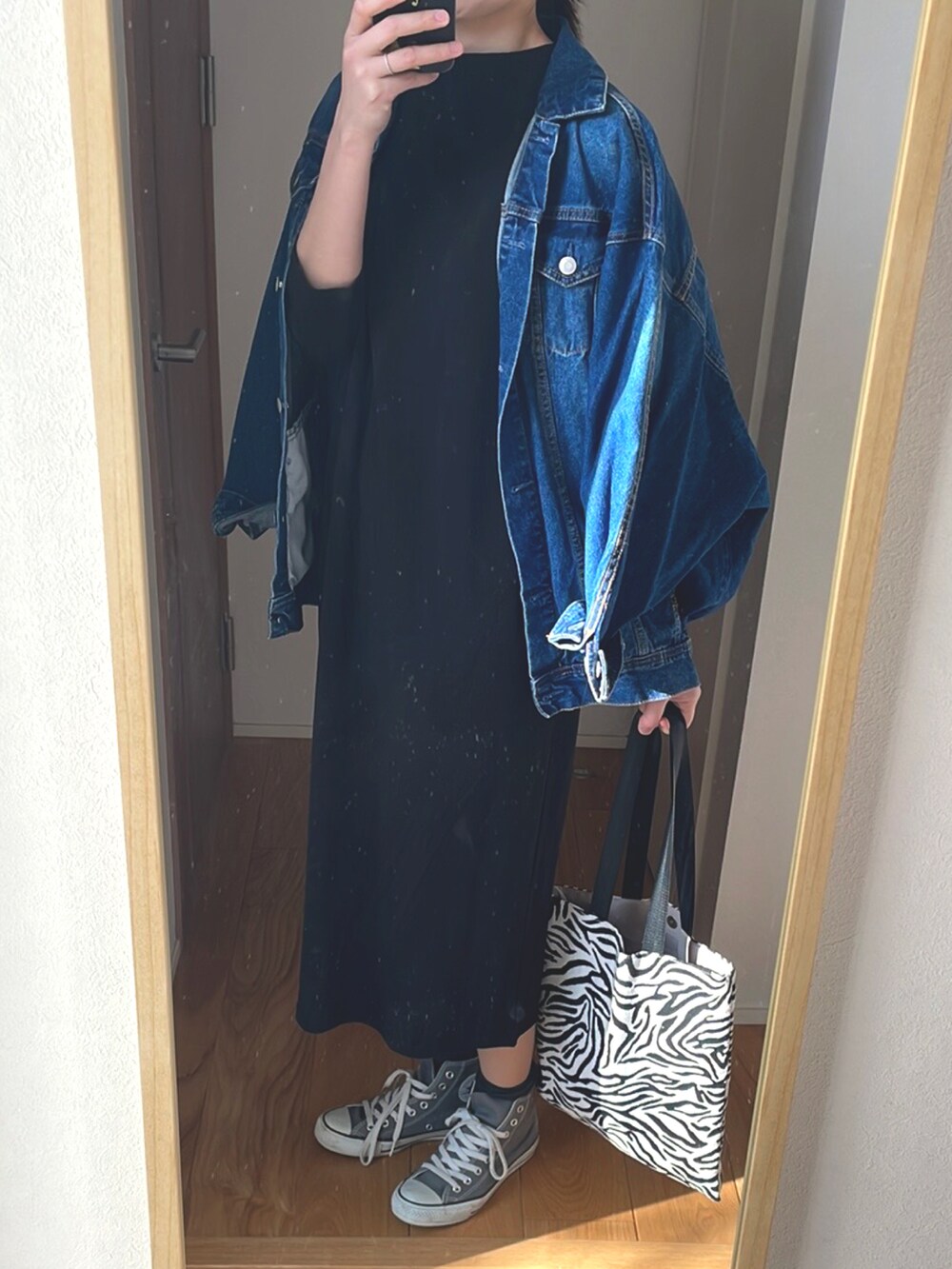 ブルー系のデニムジャケット、ブラック系のワンピース/ドレス、グレー系のスニーカーを着用したレディースの春コーディネートの2枚目の写真