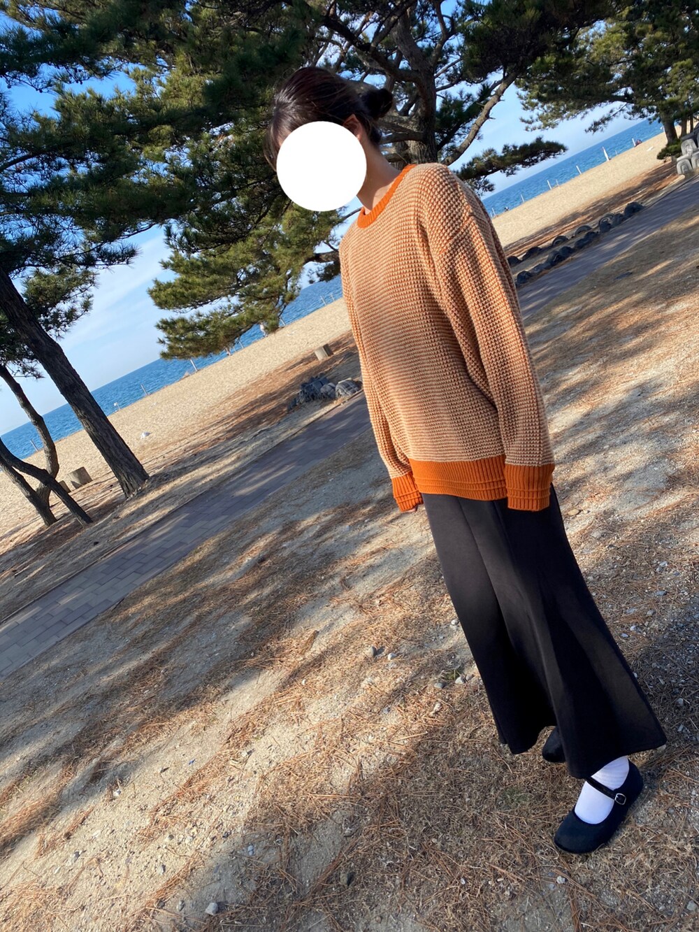 ブラック系のスカート、オレンジ系のニット/セーターを着用したレディースの冬コーディネートの2枚目の写真