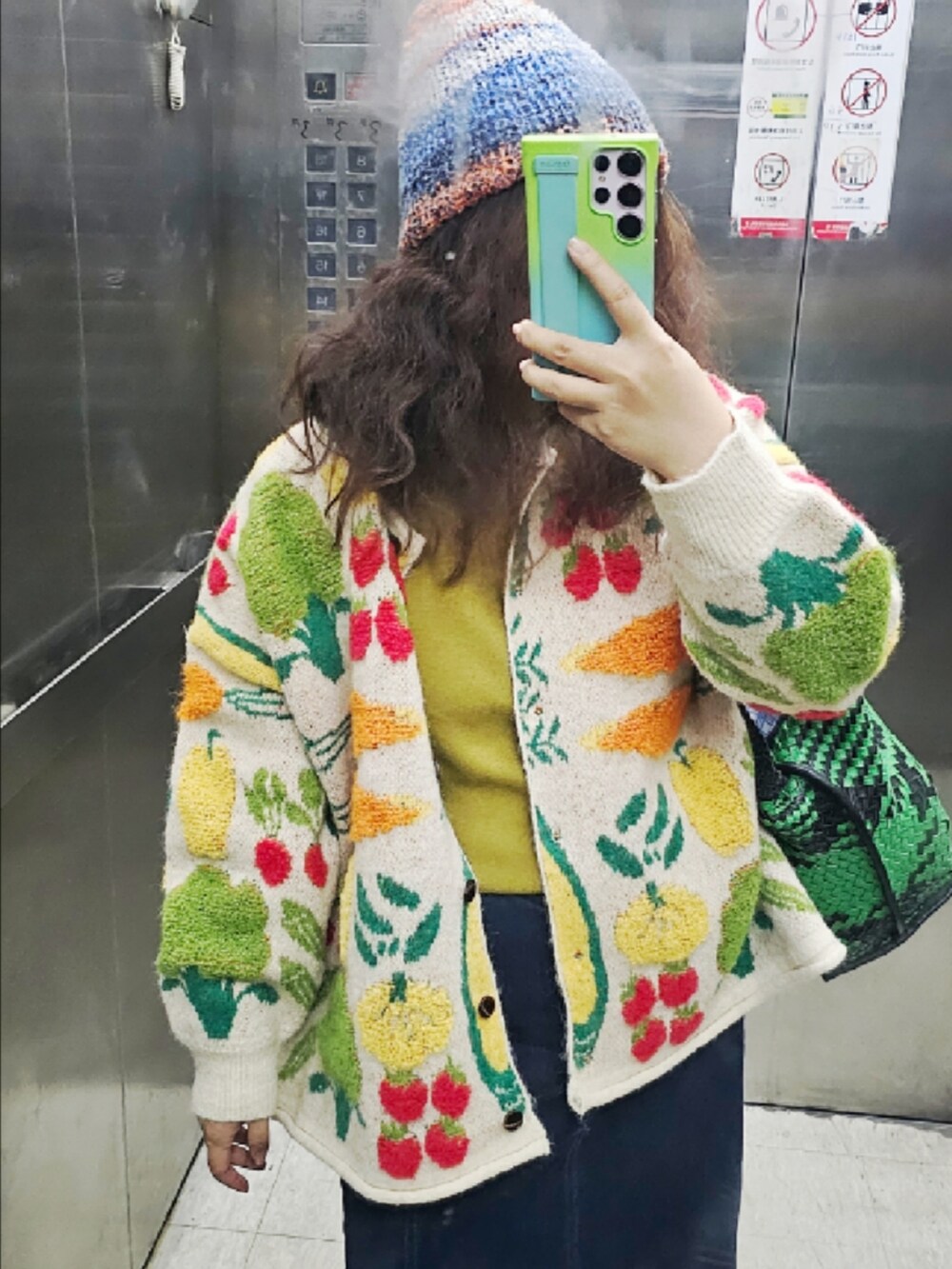 レッド系のサンダル、グリーン系のショルダーバッグ、ブルー系のニットキャップ/ビーニーを着用したレディースの冬コーディネートの2枚目の写真