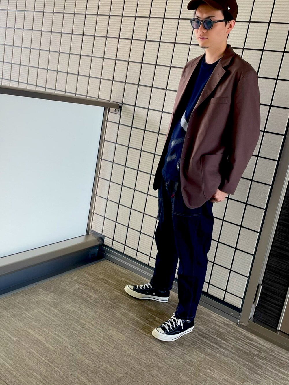 ブラウン系のテーラードジャケット、ブルー系のトップス、ブルー系のデニムパンツを着用したメンズの秋コーディネートの2枚目の写真