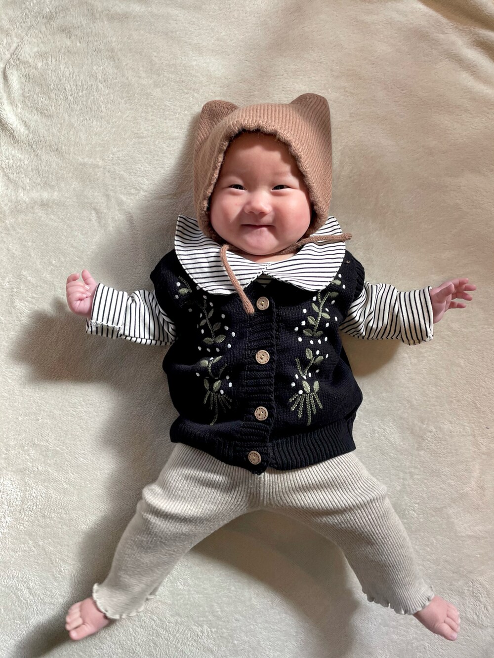 ブラック系のベスト、ベージュ系のセットアップ、ブラウン系のヘアバンドを着用したキッズの冬コーディネートの5枚目の写真