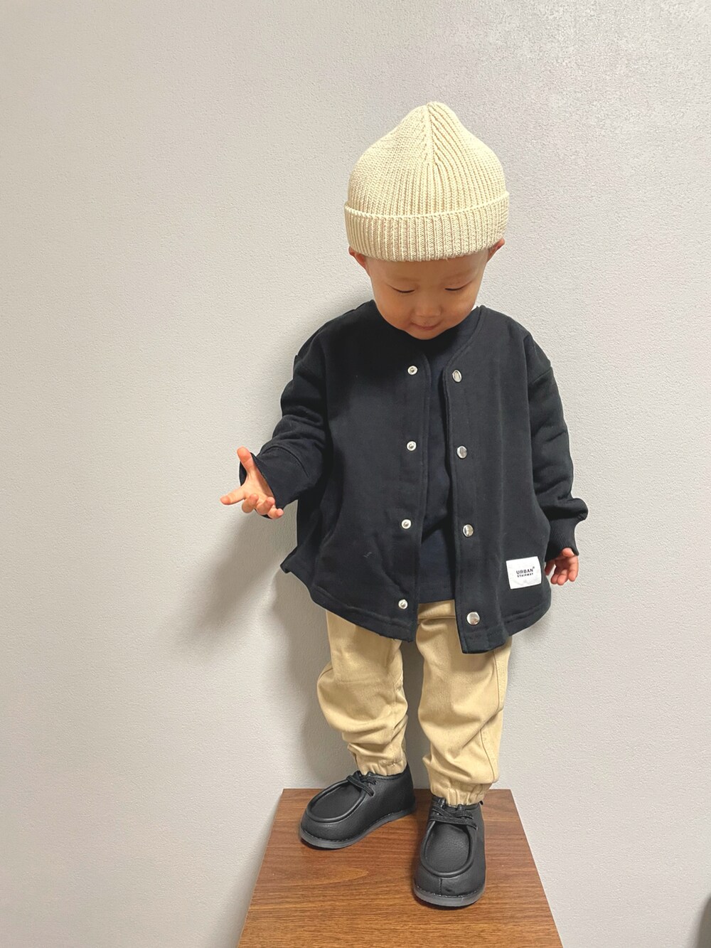ブラック系のTシャツ/カットソー、ブラック系のノーカラージャケット、ベージュ系のパンツを着用したキッズの冬コーディネートの2枚目の写真