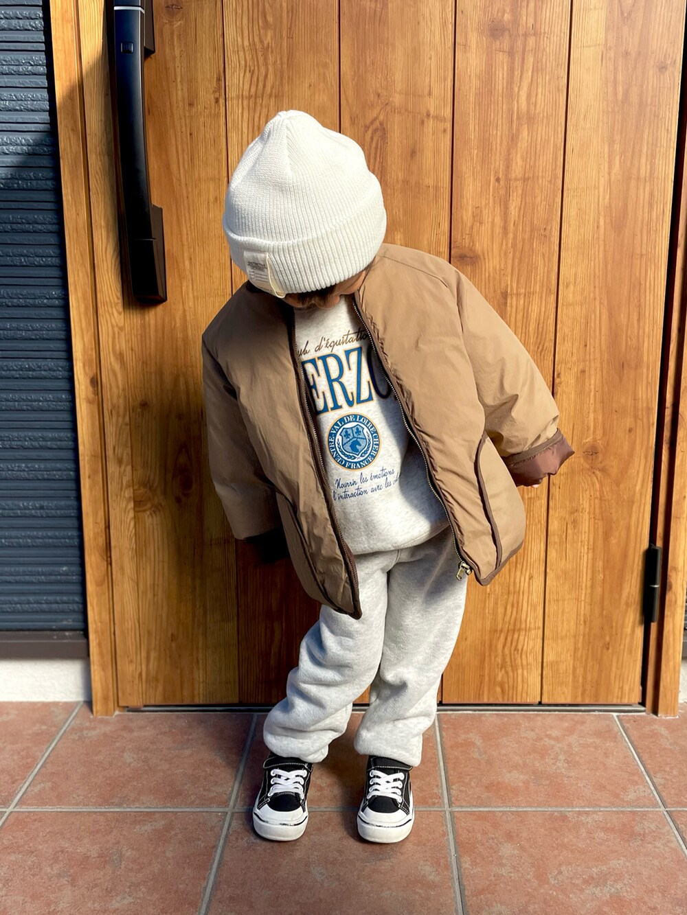 グレー系のスウェット、ブラウン系のノーカラージャケット、グレー系のスウェットパンツを着用したキッズの冬コーディネートの5枚目の写真