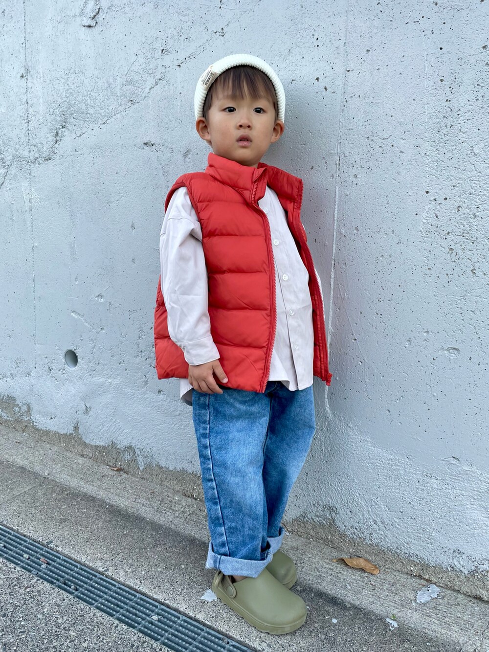 ベージュ系のシャツ/ブラウス、オレンジ系のダウンベスト、ブルー系のデニムパンツを着用したキッズの秋コーディネートの2枚目の写真