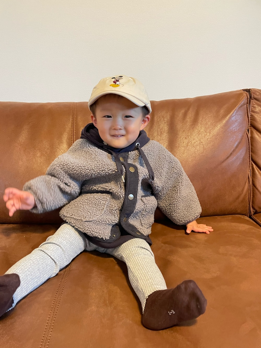 パープル系のパーカー、グレー系のノーカラージャケット、ベージュ系のキャップを着用したキッズの冬コーディネートの3枚目の写真