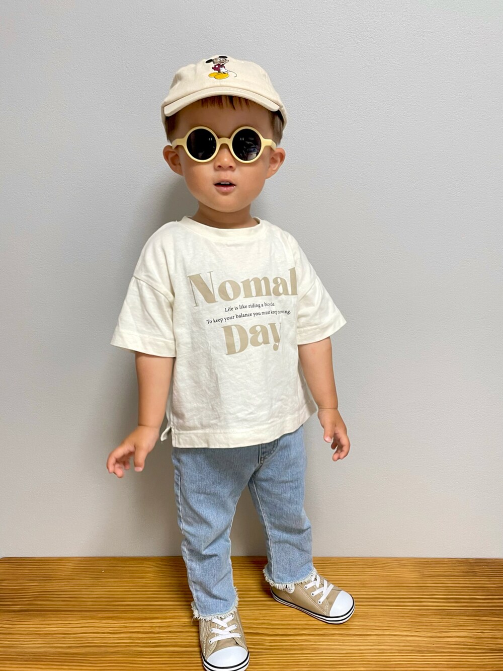 ベージュ系のTシャツ/カットソー、ベージュ系のスニーカー、ブルー系のデニムパンツを着用したキッズの春コーディネートの4枚目の写真