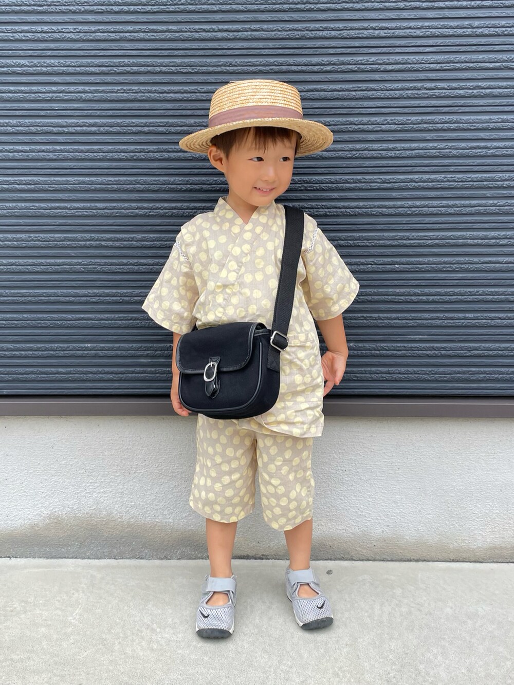ブラック系のショルダーバッグ、グレー系のスニーカー、ブラウン系のハットを着用したキッズの夏コーディネートの2枚目の写真