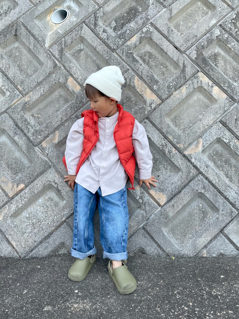 ベージュ系のシャツ/ブラウス、オレンジ系のダウンベスト、ブルー系のデニムパンツを着用したキッズの秋コーディネートの5枚目の写真