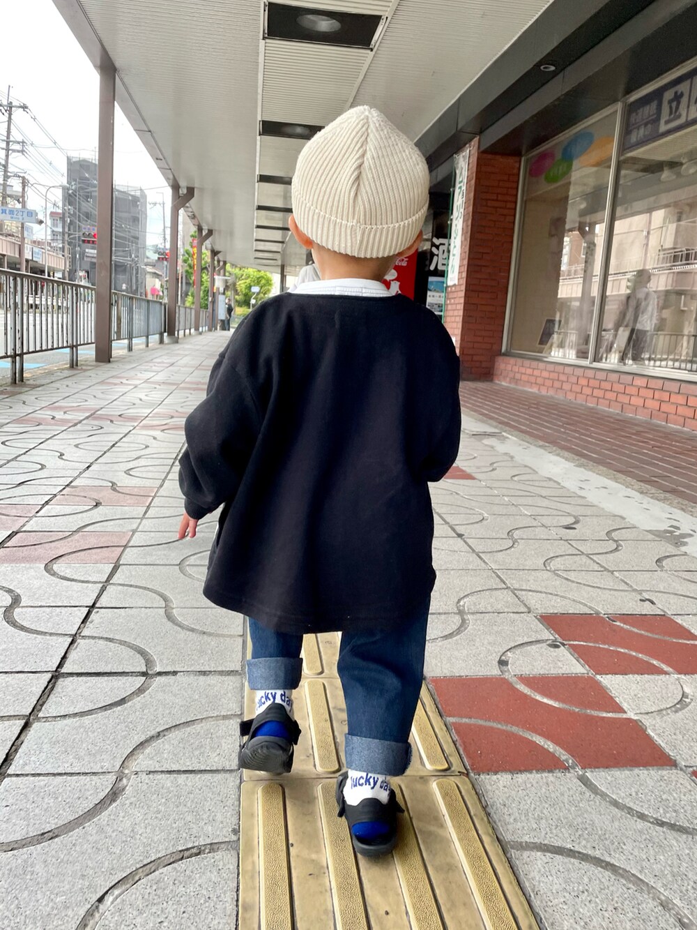 ブラック系のノーカラージャケット、ホワイト系のTシャツ/カットソー、ブルー系のデニムパンツを着用したキッズの春コーディネートの5枚目の写真