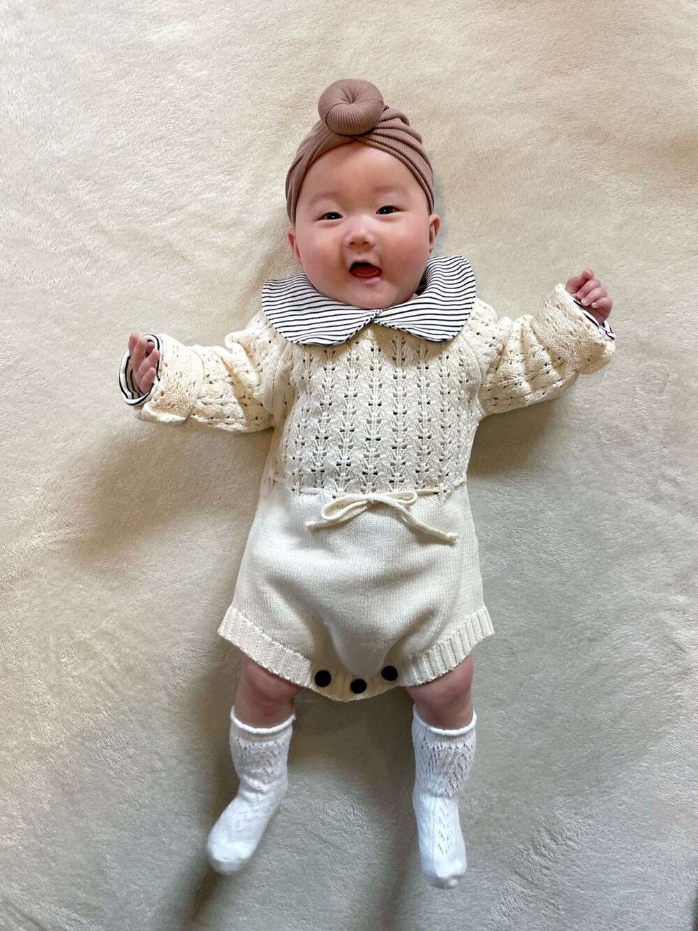 ブラウン系のヘアバンド、ブラック系のロンパース、ホワイト系のロンパースを着用したキッズの冬コーディネートの2枚目の写真