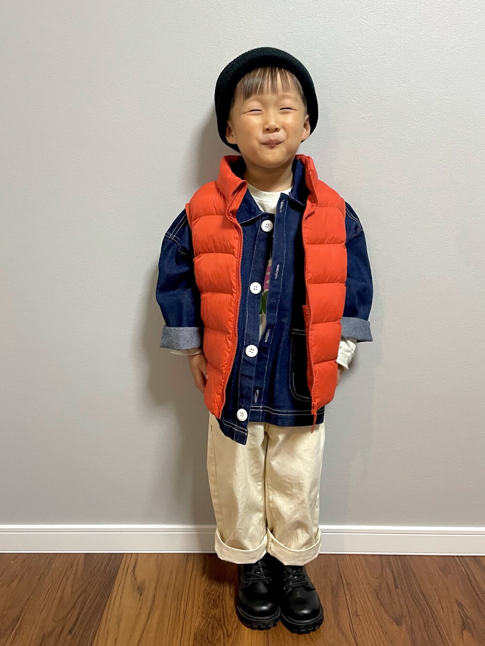 オレンジ系のダウンベスト、ブルー系のデニムジャケット、ホワイト系のデニムパンツを着用したキッズの秋コーディネートの3枚目の写真