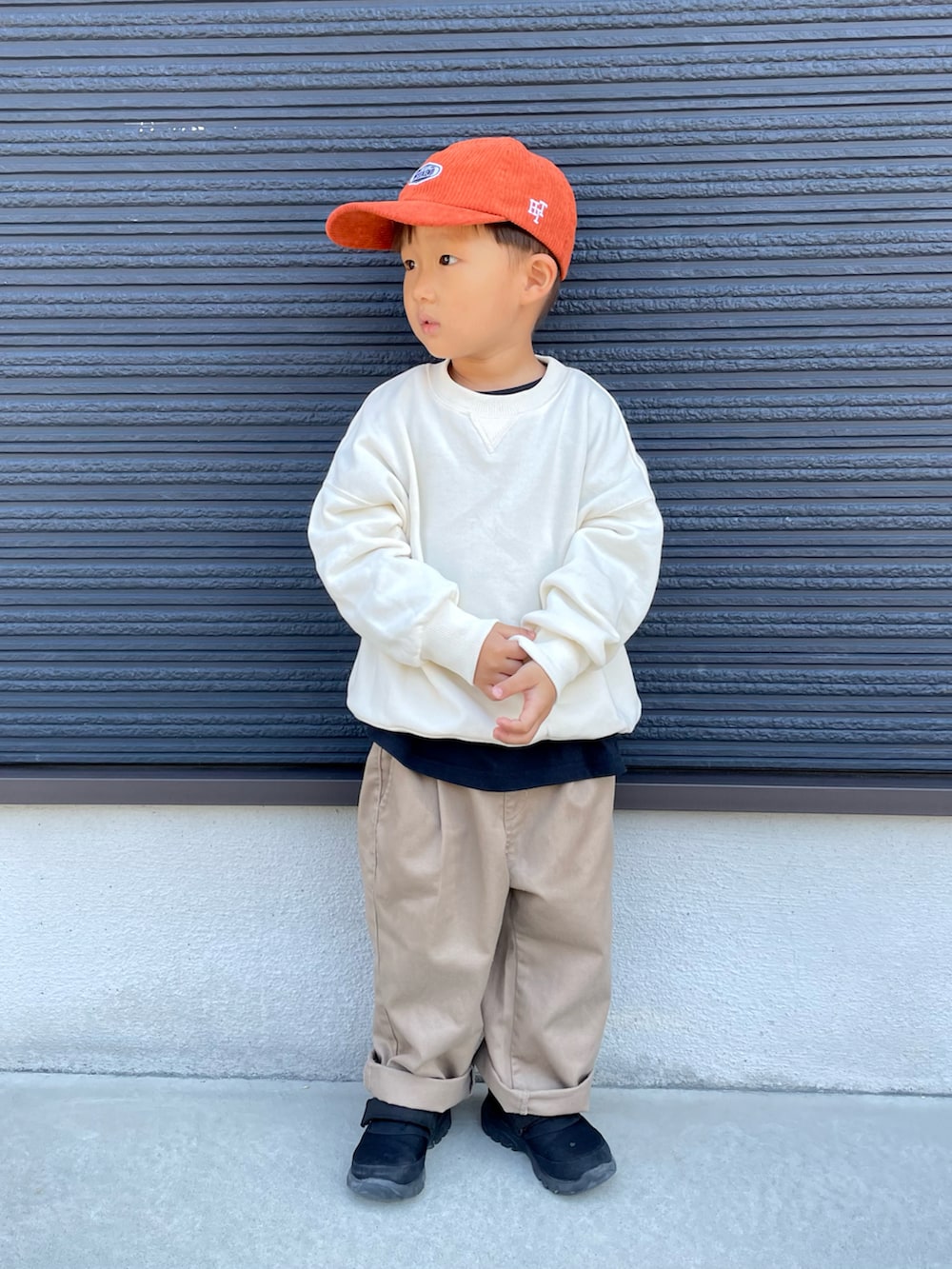 ホワイト系のスウェット、ブラック系のTシャツ/カットソー、ベージュ系のチノパンツを着用したキッズの秋コーディネートの2枚目の写真