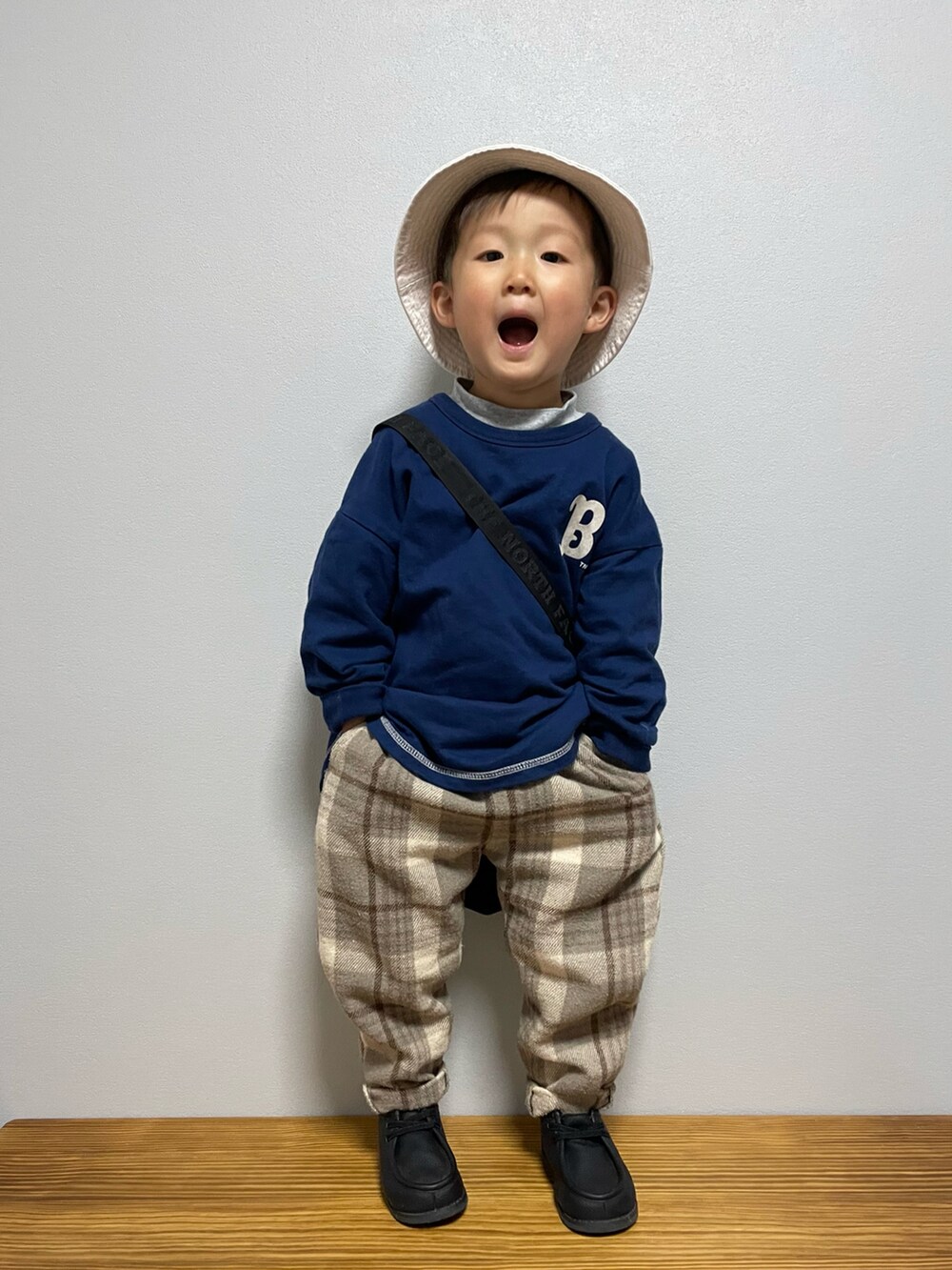 グリーン系のスウェット、ブラック系のブーツ、ブラック系のショルダーバッグを着用したキッズの春コーディネートの3枚目の写真