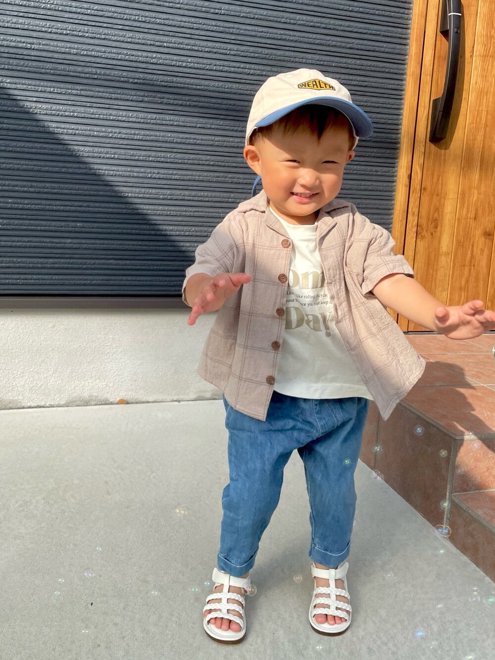 ベージュ系のセットアップ、ベージュ系のTシャツ/カットソー、ブルー系のデニムパンツを着用したキッズの夏コーディネートの2枚目の写真