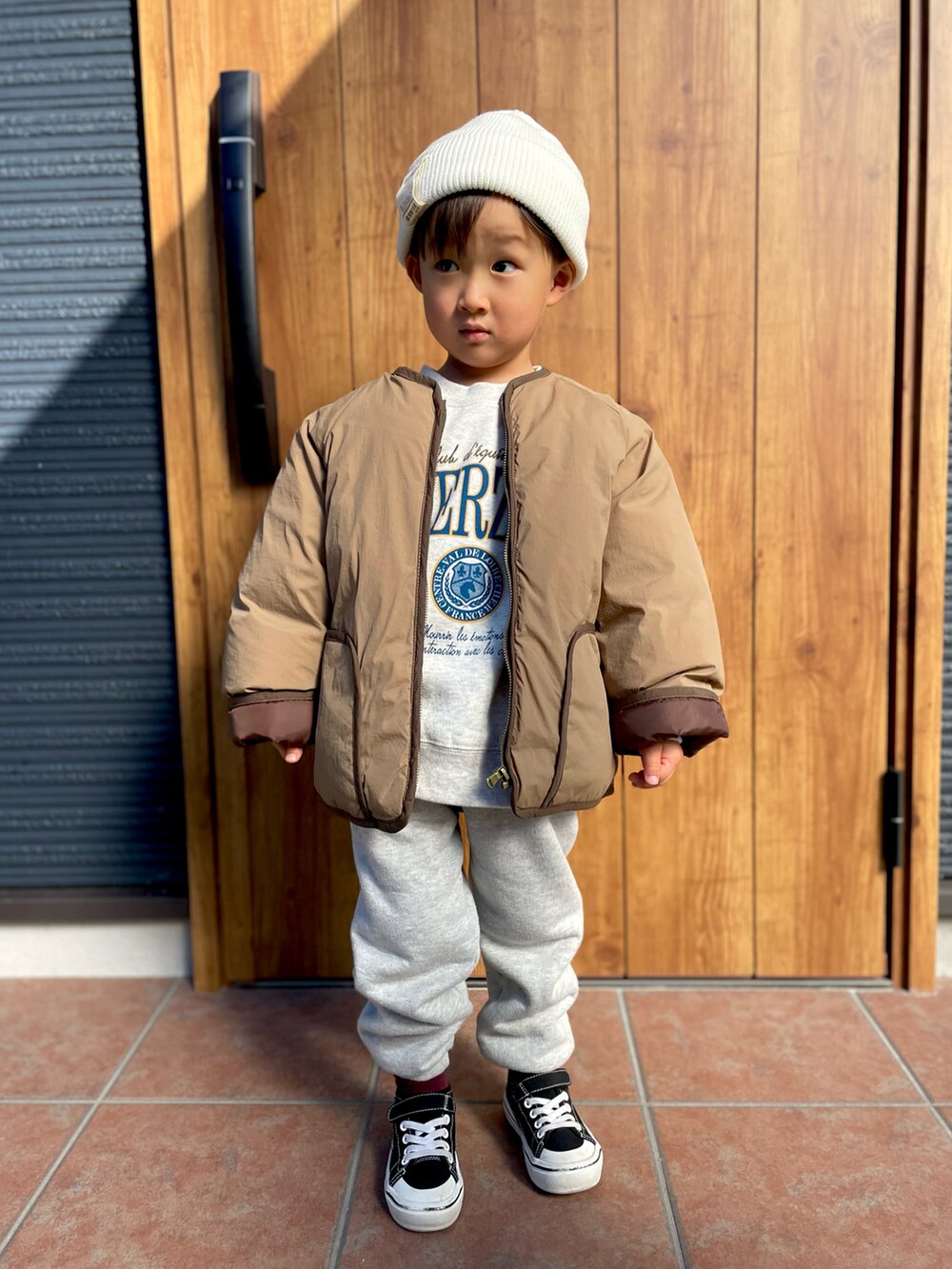 グレー系のスウェット、ブラウン系のノーカラージャケット、グレー系のスウェットパンツを着用したキッズの冬コーディネートの2枚目の写真