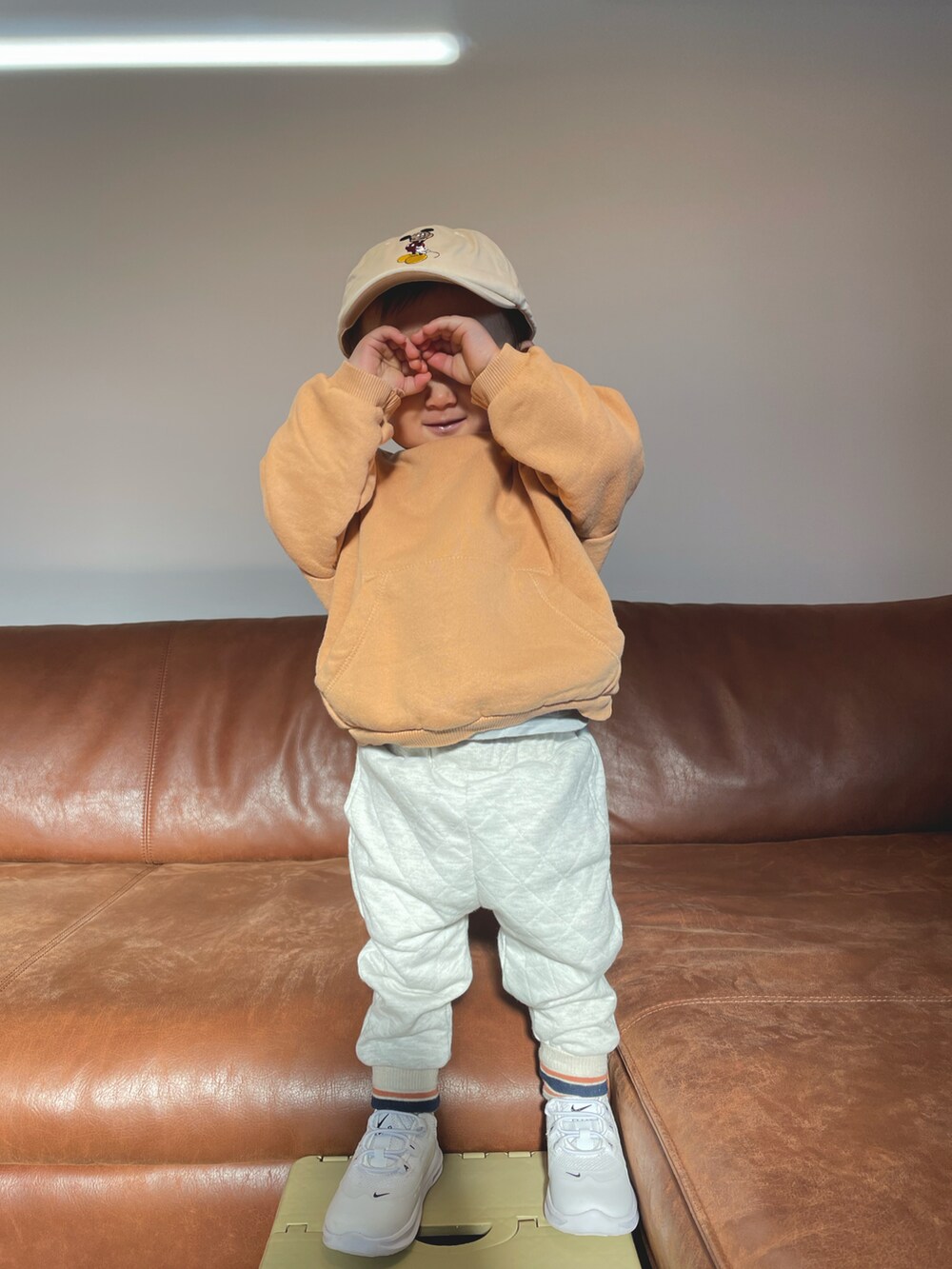 オレンジ系のスウェット、ホワイト系のその他パンツ、ベージュ系のキャップを着用したキッズの冬コーディネートの3枚目の写真