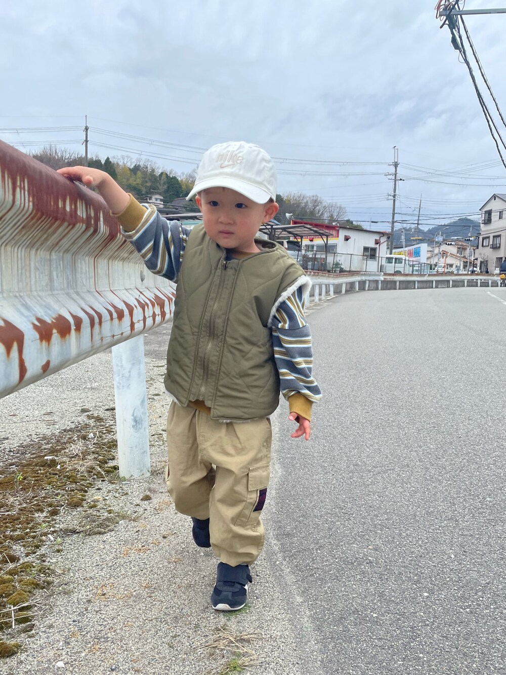 グリーン系のダウンベスト、グレー系のスウェット、ベージュ系のカーゴパンツを着用したキッズの春コーディネートの3枚目の写真