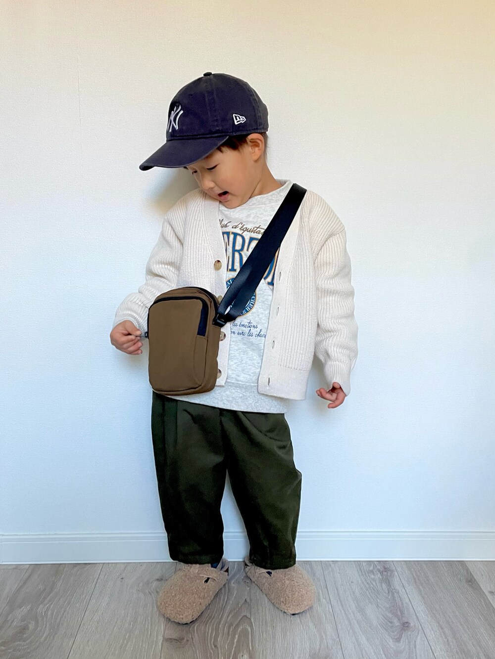 グレー系のスウェット、ブラウン系のショルダーバッグ、ホワイト系のカーディガン/ボレロを着用したキッズの冬コーディネートの2枚目の写真
