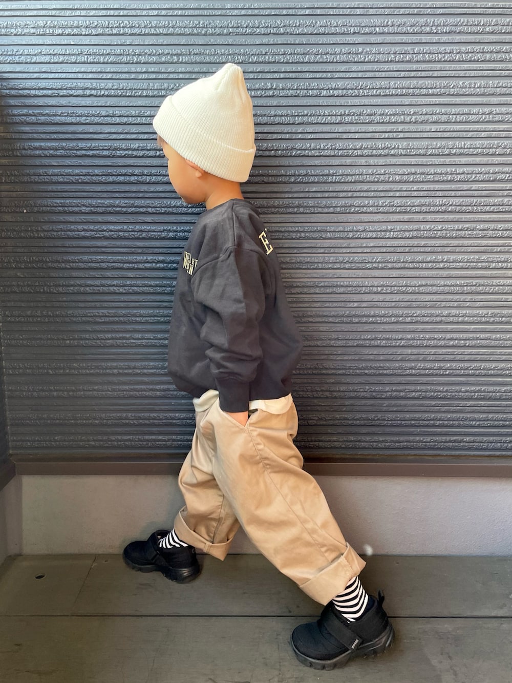 ブラック系のスニーカー、ブラック系のスウェット、ベージュ系のチノパンツを着用したキッズの秋コーディネートの4枚目の写真