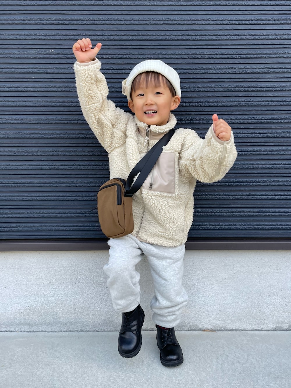 ブラウン系のショルダーバッグ、ベージュ系のその他アウター、グレー系のスウェットパンツを着用したキッズの冬コーディネートの4枚目の写真