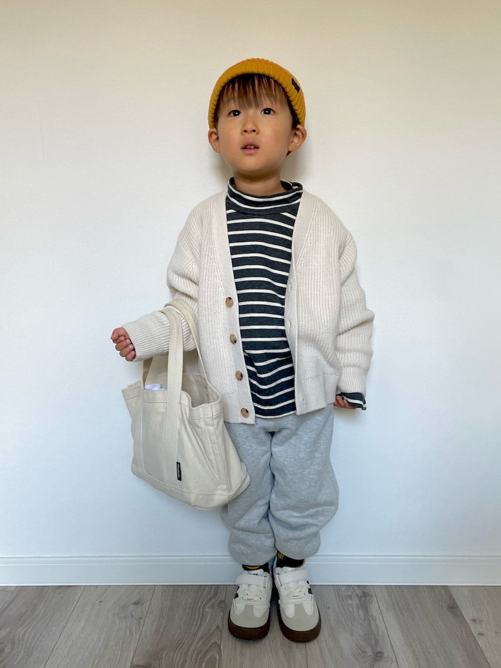 ブラック系のTシャツ/カットソー、ホワイト系のカーディガン/ボレロ、グレー系のスウェットパンツを着用したキッズの冬コーディネートの3枚目の写真