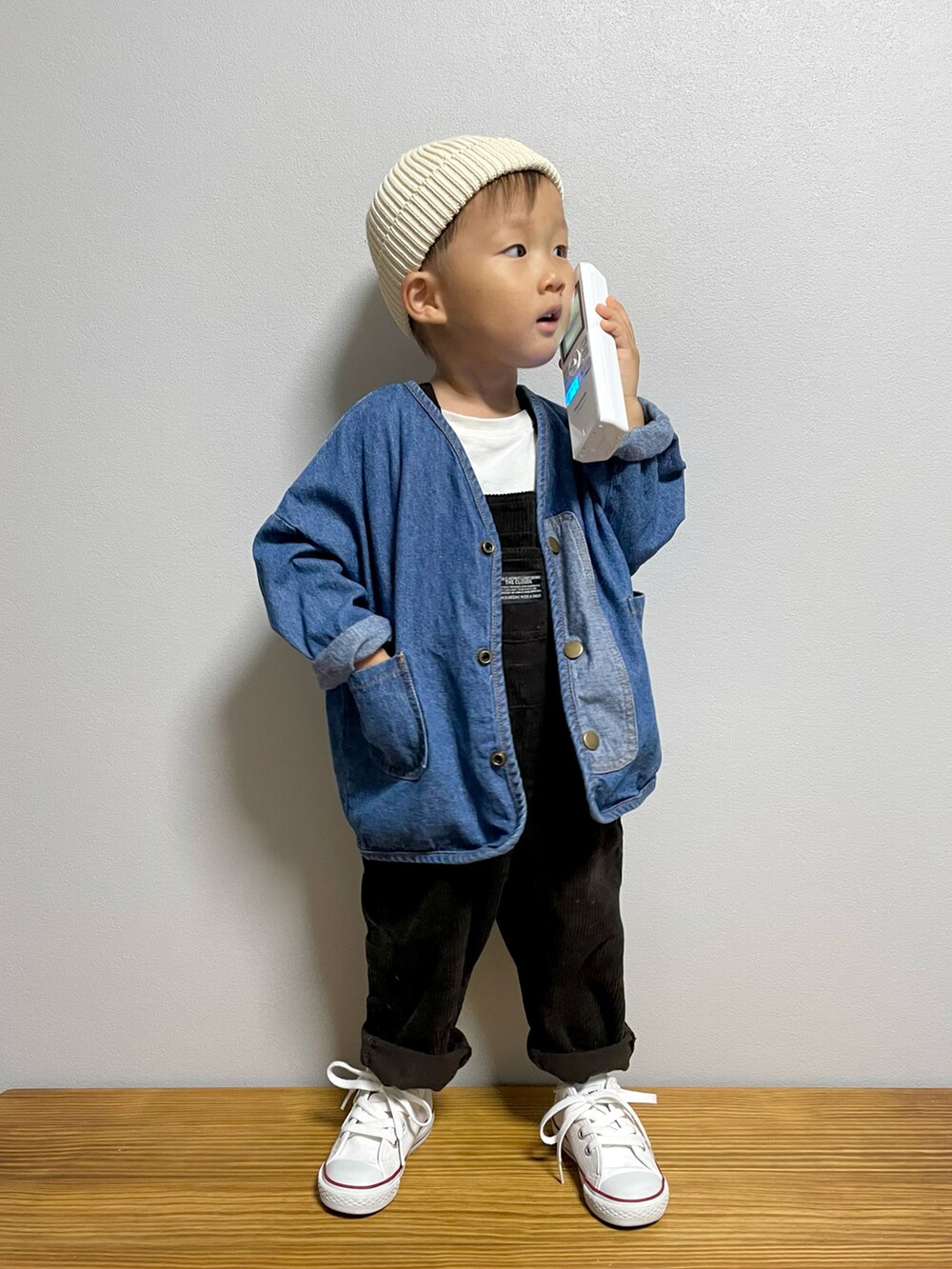 ブルー系のデニムジャケット、グレー系のサロペット/オーバーオール、ホワイト系のスニーカーを着用したキッズの秋コーディネートの2枚目の写真