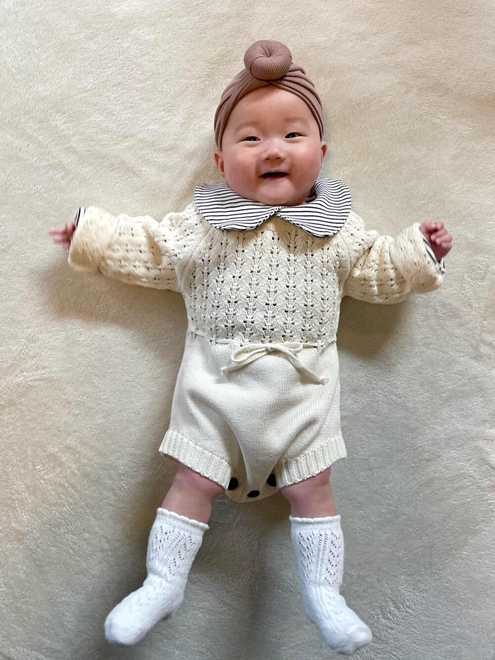 ブラウン系のヘアバンド、ブラック系のロンパース、ホワイト系のロンパースを着用したキッズの冬コーディネートの3枚目の写真