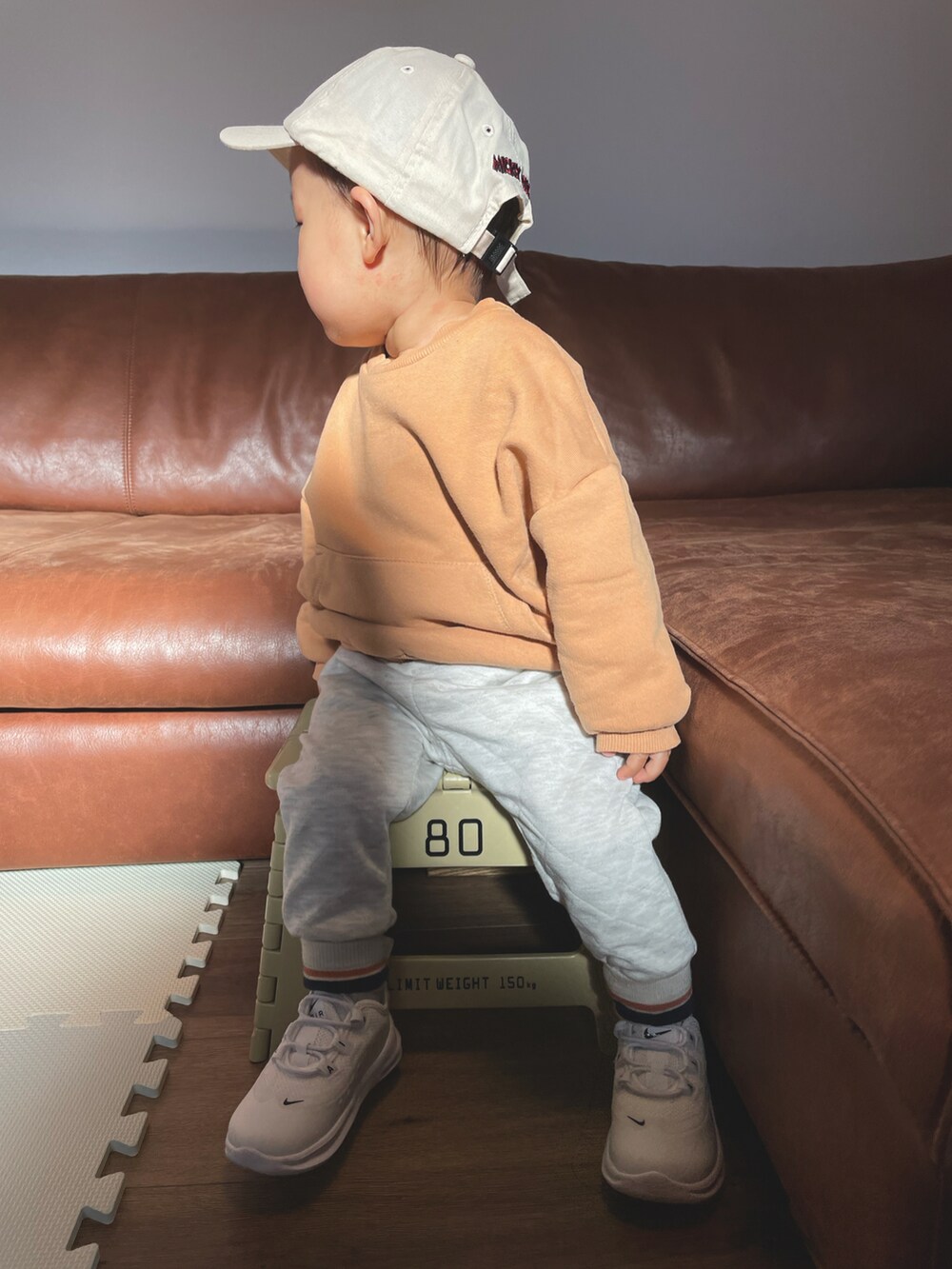 オレンジ系のスウェット、ホワイト系のその他パンツ、ベージュ系のキャップを着用したキッズの冬コーディネートの5枚目の写真