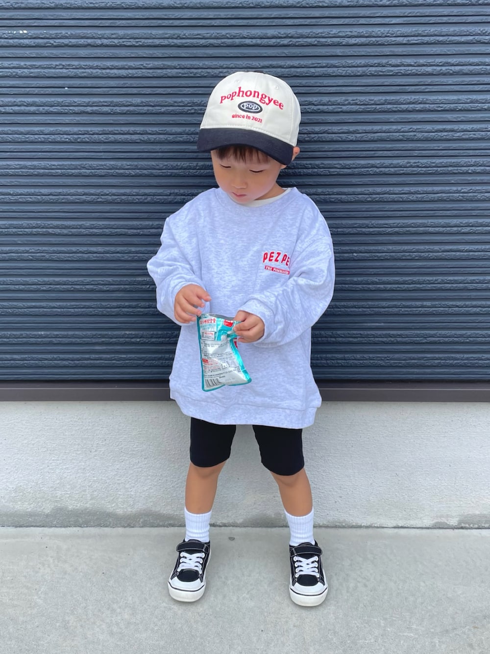 グレー系のスウェット、ブラック系のスニーカー、ブラック系のキャップを着用したキッズの秋コーディネートの4枚目の写真