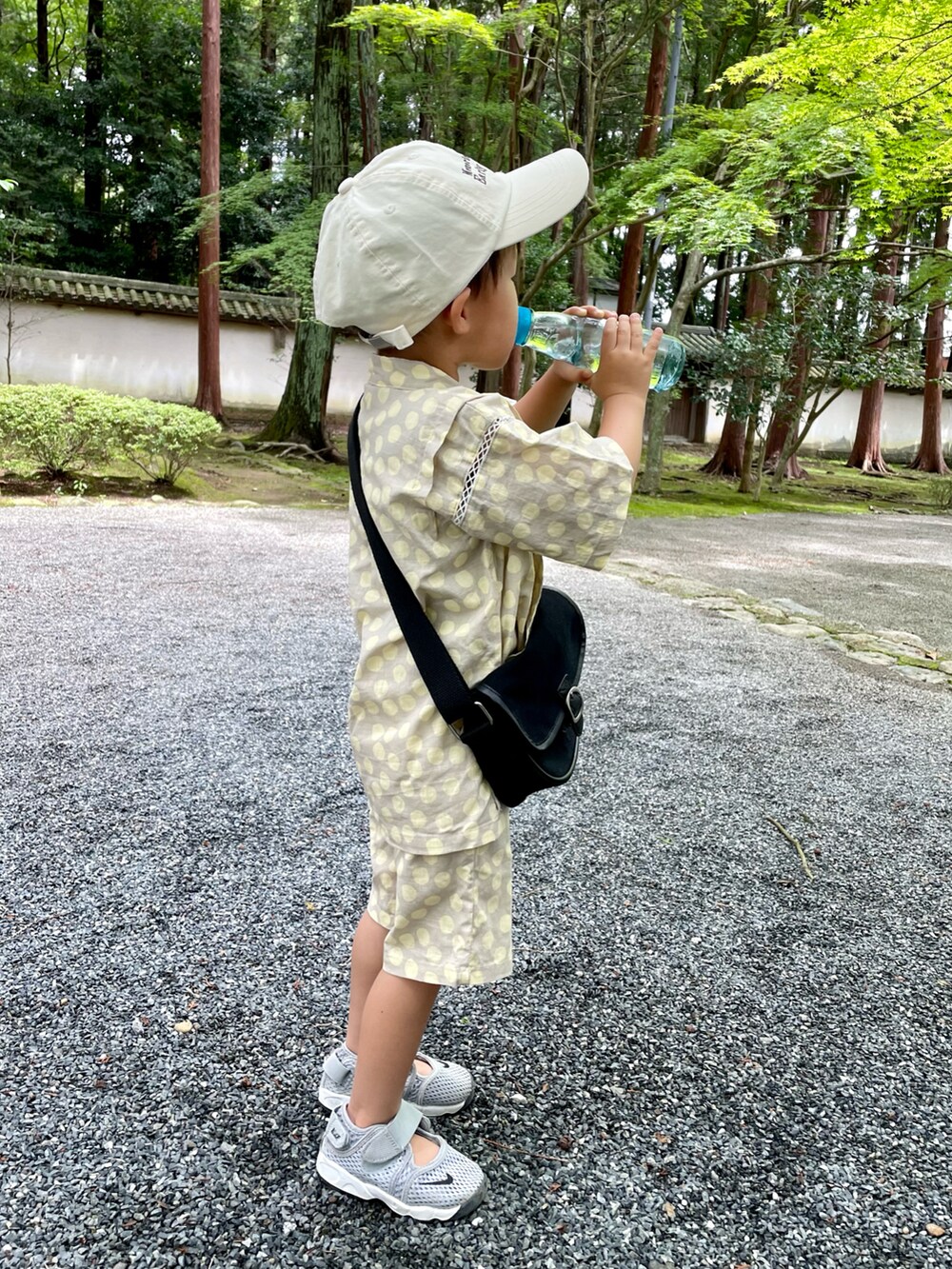 ブラック系のショルダーバッグ、グレー系のスニーカー、ブラウン系のハットを着用したキッズの夏コーディネートの4枚目の写真