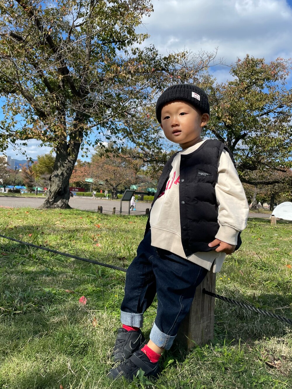 ベージュ系のスウェット、ブラック系のダウンベスト、ブルー系のデニムパンツを着用したキッズの秋コーディネートの2枚目の写真