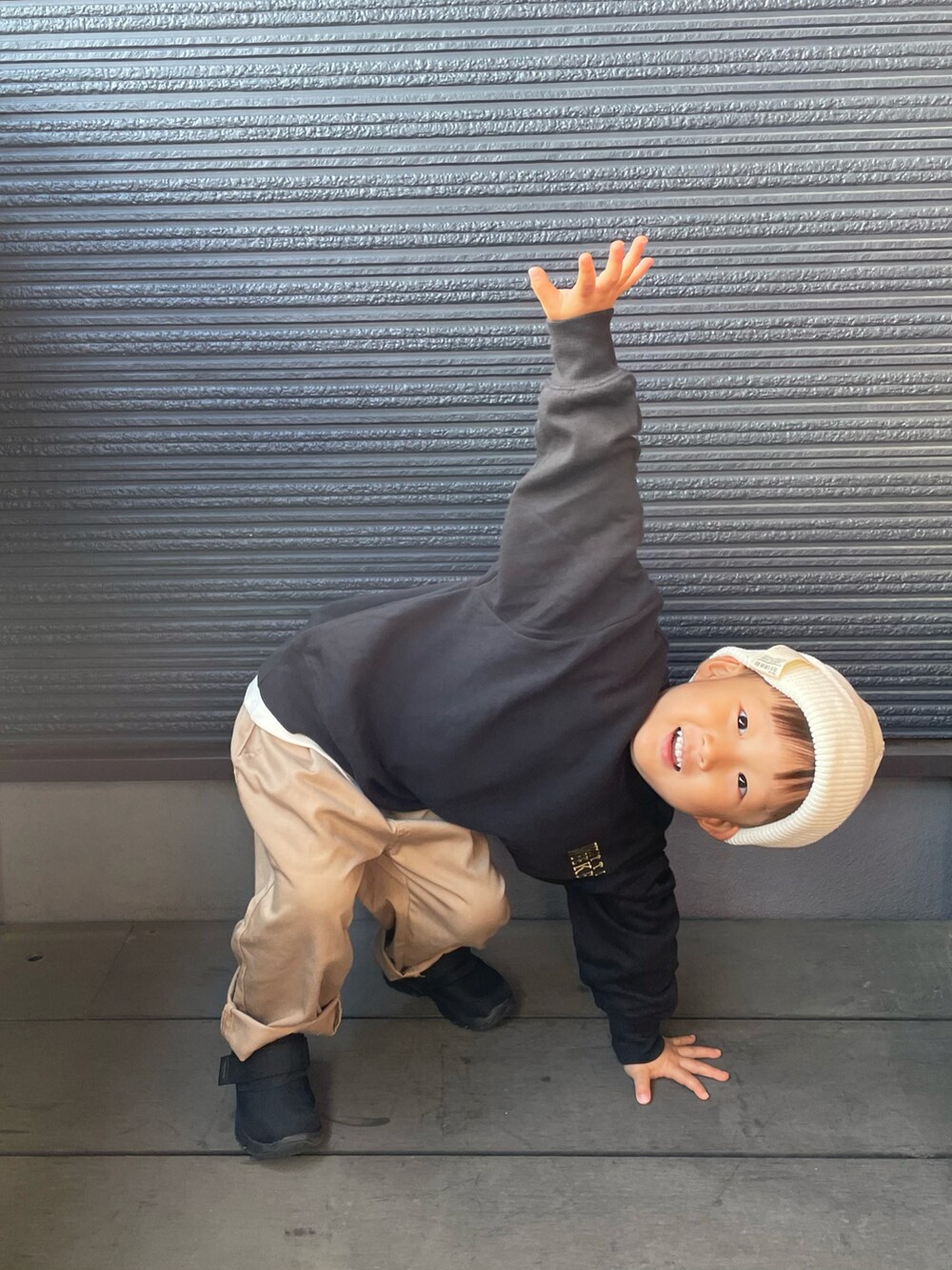 ブラック系のスニーカー、ブラック系のスウェット、ベージュ系のチノパンツを着用したキッズの秋コーディネートの5枚目の写真